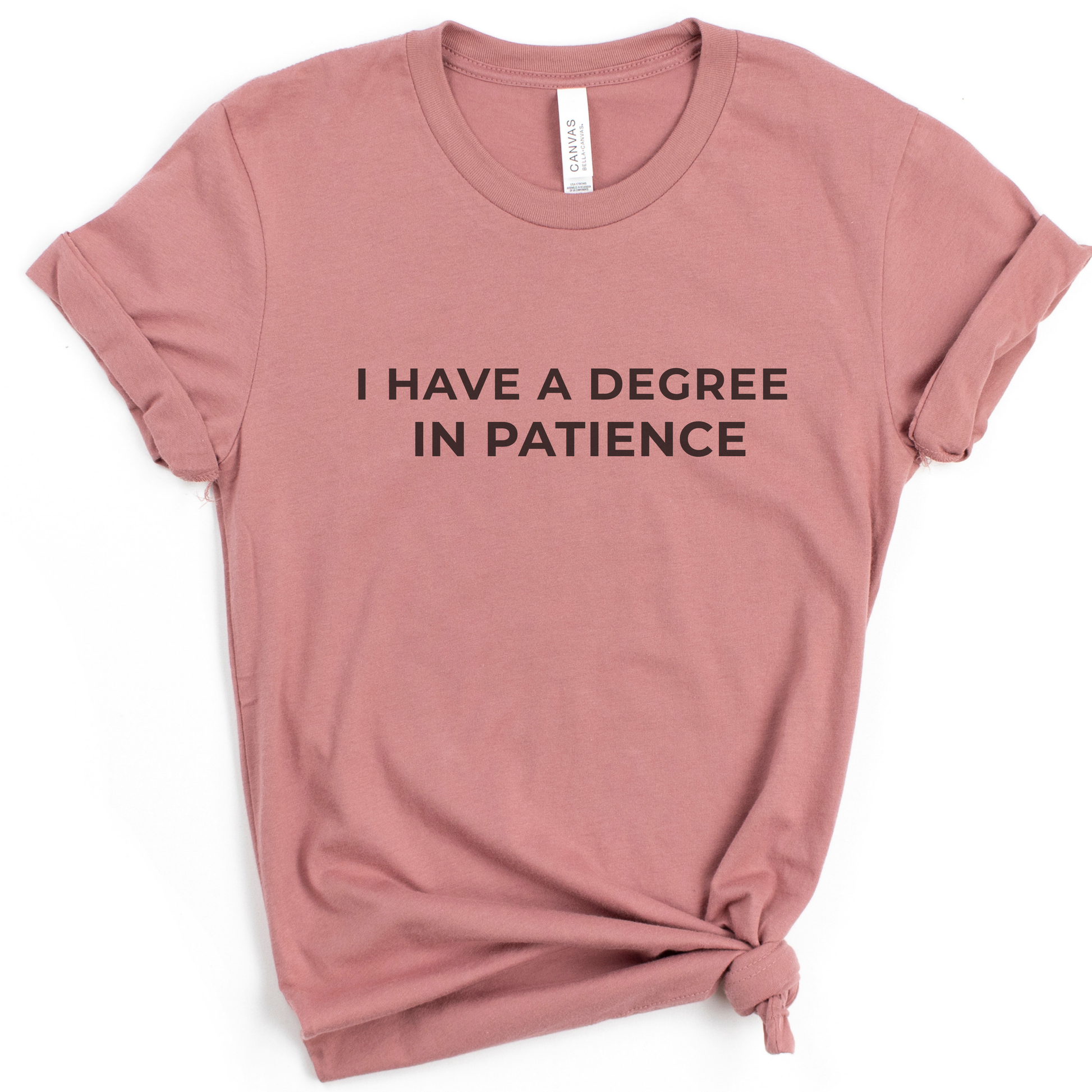Dusty rose teacher tee displaying the phrase “I Have a Degree in Patience” in a clean, minimal flat lay.