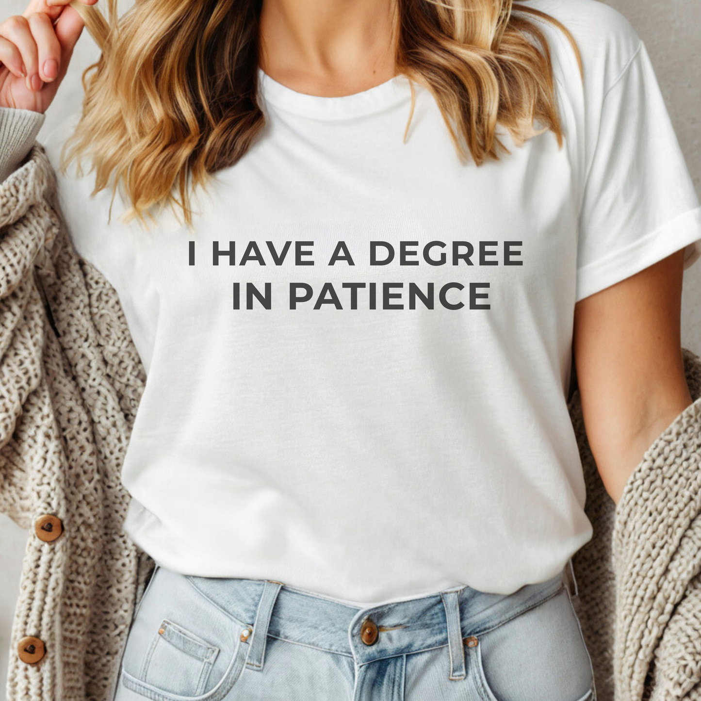 Cream teacher t-shirt featuring the phrase “I Have a Degree in Patience,” styled in a cozy, minimal flat lay.