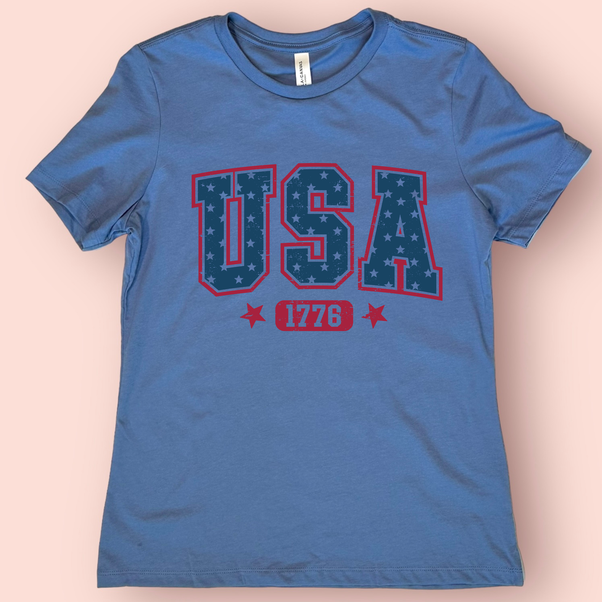 Blue t-shirt with 'USA 1776' text on a beige background