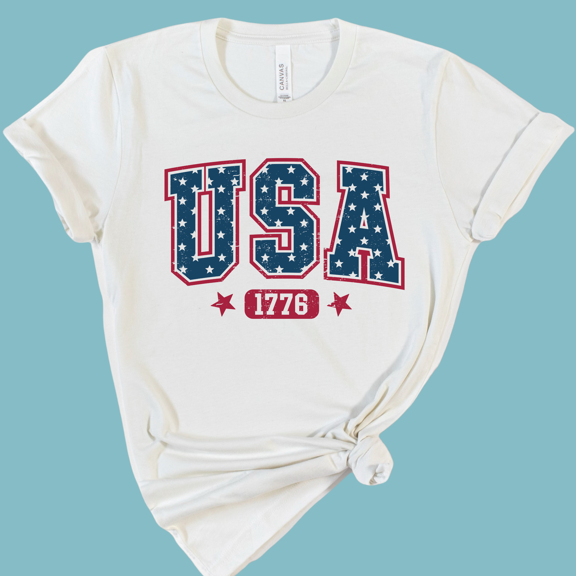 White t-shirt with 'USA 1776' design on a light blue background