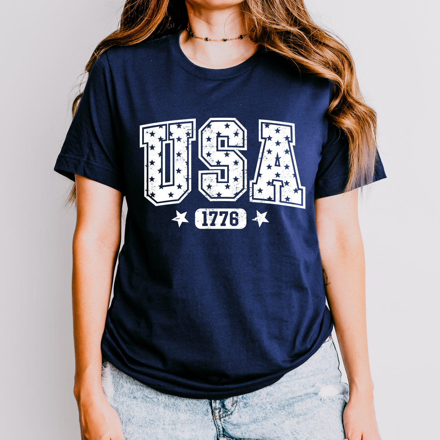 Person wearing a navy blue t-shirt with 'USA 1776' print on a plain background