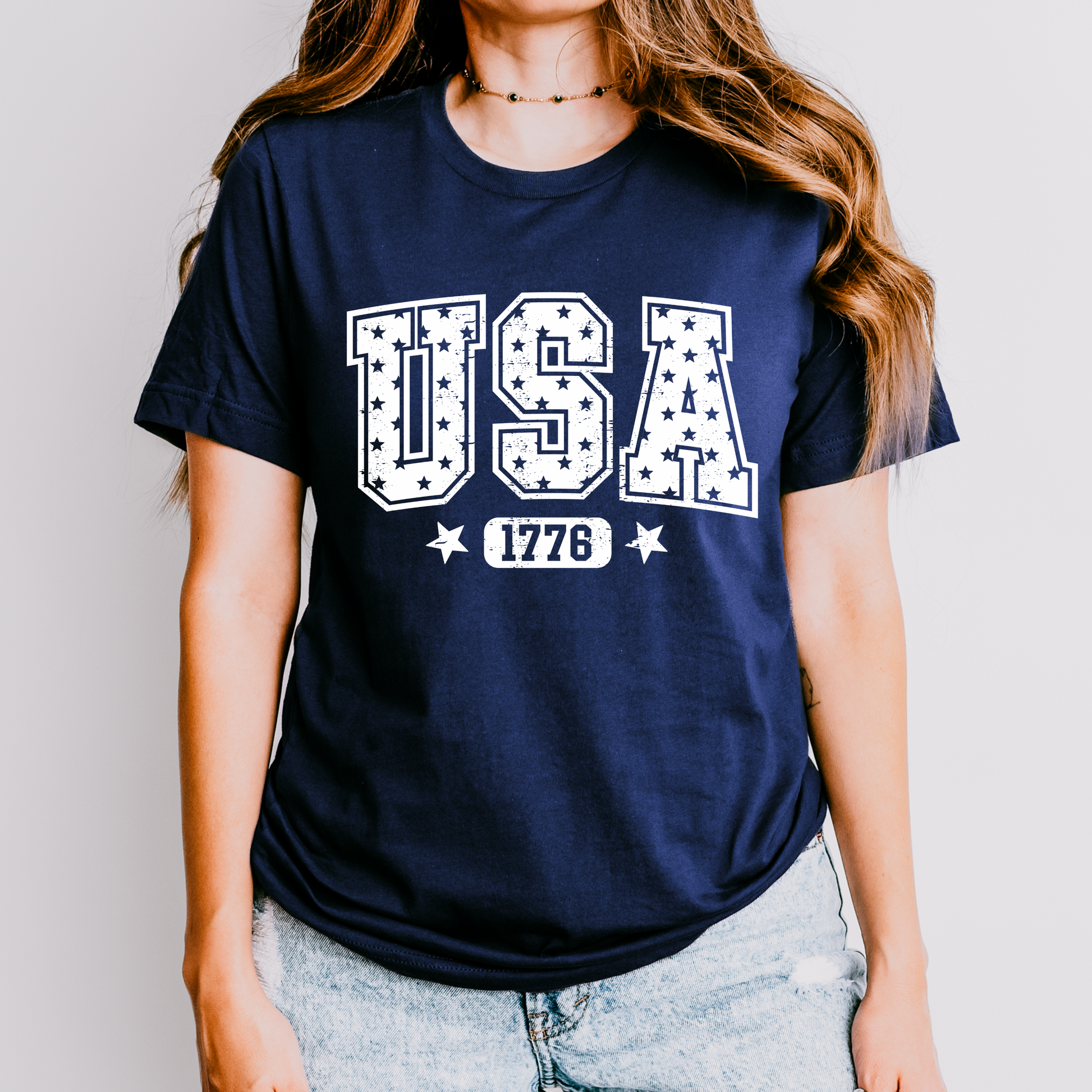 Person wearing a navy blue t-shirt with 'USA 1776' print on a plain background