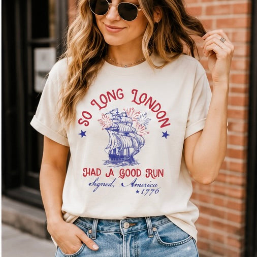 Woman wearing a t-shirt with 'So Long London, Had a Good Run' design against a brick wall.